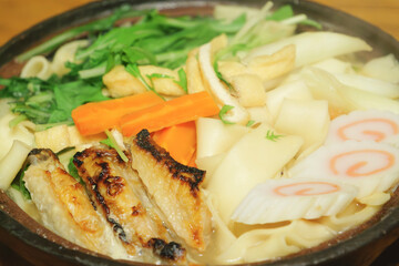 Nagoya's specialty, Kishimen noodle stew in miso broth, Japanese style noodles, deep-fried tofu, carrots, chicken, and Naruto