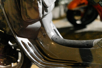 a classic scooter parked under the city lights at night. The gleaming chrome details and the iconic...