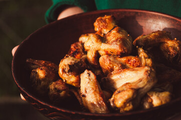 Hands holding plate with grilled chicken wings
