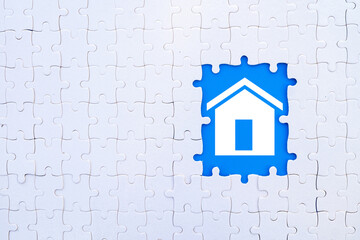 Puzzle pieces with a missing piece showing a house icon in blue background, symbolizing home, real estate, solutions, or building. Concept for finding the right fit, home search, or property.