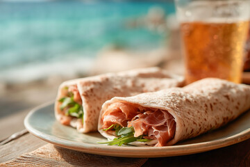 Deliziose piadine arrotolate con il prosciutto crudo e un bicchiere di birra sul tavolo vicino al mare