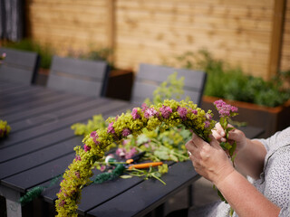The hands of a woman building a midsummer wreath of flowers for the traditional swedish midsummer celebration
