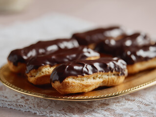 Chocolate drenched eclairs on golden plate, creating tempting dessert display