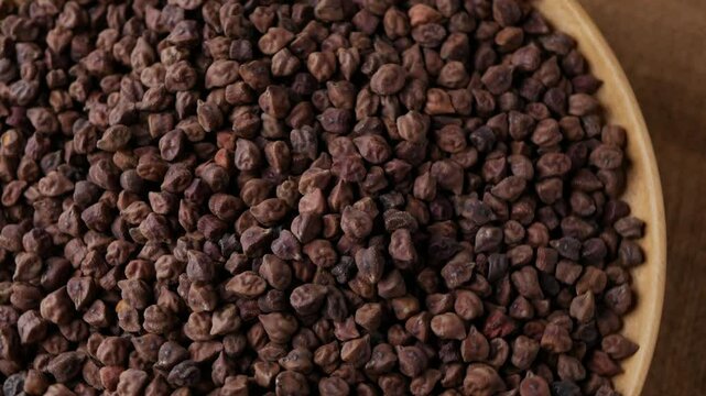 Raw Dark Brown Chickpeas (Kala Chana) on a rustic wooden table. Dry Balck chickpea (ceci neri) background close up. 