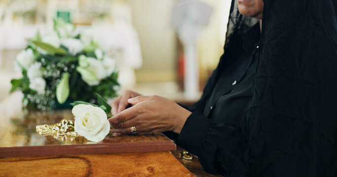 Hands, person and coffin with rose at funeral for farewell, mourning death and goodbye at burial ceremony. Woman, widow and rip with flower for respect, memorial service and emotional for loss