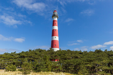 Red and white historic lighthouse on top of the dune in Ameland, Netherlands