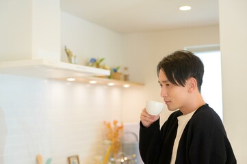 キッチンでコーヒーを片手に朝のひとときを楽しむ男性の穏やかな表情