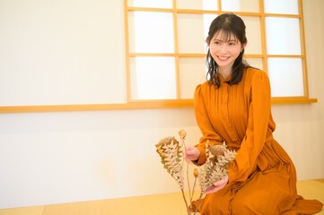 ドライフラワーを手にして優しく微笑む若い女性のポートレート