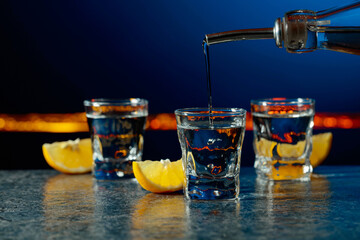 Vodka and lemon slices on a dark blue background.