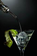 Vodka or gin is poured into a glass with ice.