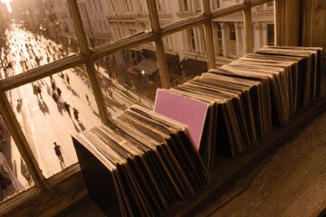Naklejka premium Vinyl records lined up in a sunlit window during a busy street gathering