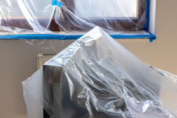 Protective painting foil covering furniture and objects during room renovation and painting work,...