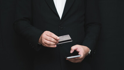Businessman making online payment with credit card and smartphone. Concept of mobile banking, e-commerce, digital finance, and secure transaction technology.