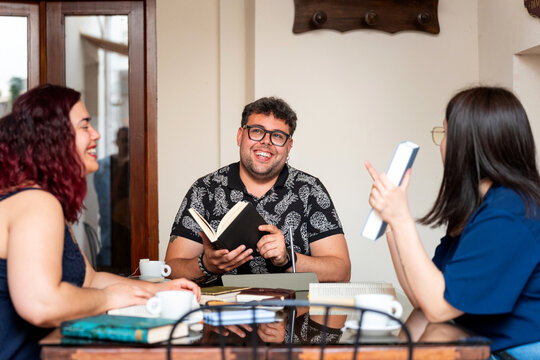 Friends reading and talking about books at a cafe table
