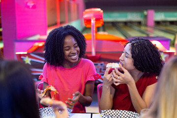 Friends enjoying pizza and conversation at bowling alley