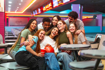 Happy friends having fun and laughing together at bowling alley