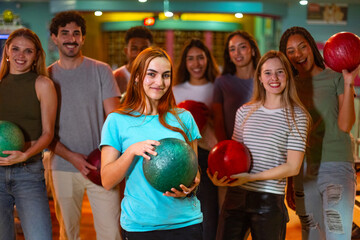 Group of friends holding bowling balls, ready for fun night out