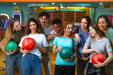 Group of young people having fun, holding bowling balls, ready to play