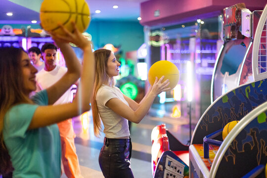 Friends playing arcade basketball game, having fun together