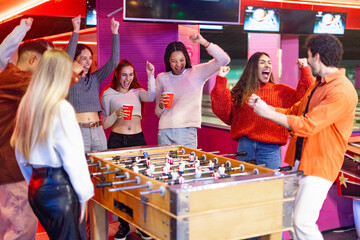 Friends cheering and celebrating while playing foosball in bowling alley