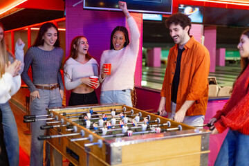 Friends playing foosball and having fun at bowling alley