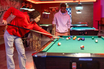 Young people playing billiards in a pool hall