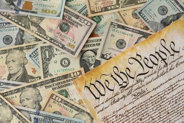 American US dollars money bills with coins and constitution close up on american flag