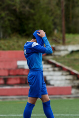 young soccer player in blue suit holds his head in his shirt in despair after losing the match © Raffaele Conti RC88