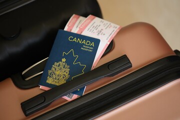 Canadian passport with tickets lies on touristic suitcase in airport hall