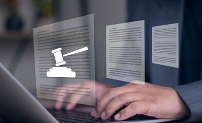 Legal documents and hammer. Lawyer is reviewing and preparing legal documents for court case. Hands are typing on laptop computer keyboard at desk.