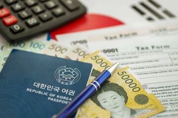 South Korean won money bills lies on table with pen, calculator, passport and tax forms