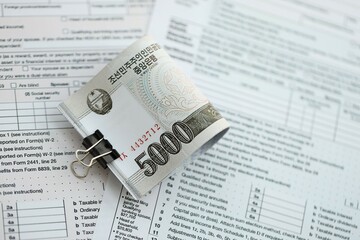 North Korean won money bills in big amount lies on table with tax forms close up