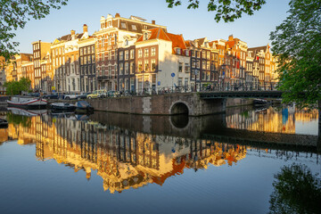 Amsterdam canal houses and bridge reflect on calm canal water