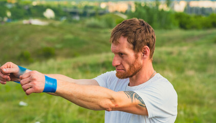 Fototapeta premium A professional sportsman in a white shirt is holding a Elastic band expander. He appears focused and determined as he prepares his shoulder and arm muscles for the workout ahead.