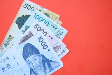 South Korean won money bills in big amount lies on red color table close up