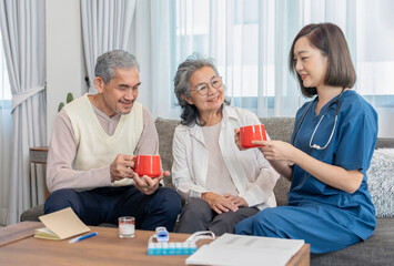 Obraz premium home health care nurse in uniform explain and advice healthy drink,milk,fruit juice or vitamins while visiting senior couple at home