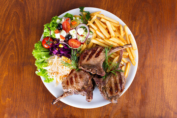 Indulge in Deliciously Grilled Lamb Chops accompanied by a Fresh Salad and Crispy Fries