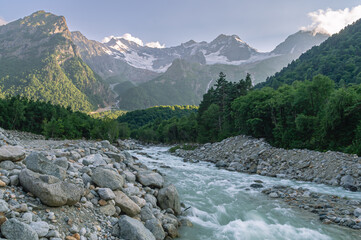 The bubbling glacial-clear water of a mountain river with large stones high in the mountains. Environmentally friendly water flows down from a glacier in the mountains. Nature in the mountains.