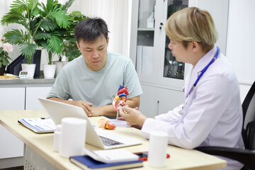 Fototapeta premium Doctor explains heart model to patient in medical office setting