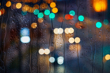 raindrops on the window and multi colored street lights at night background