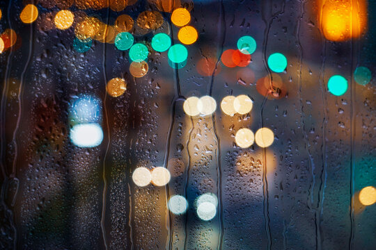 raindrops on the window and multi colored street lights at night background