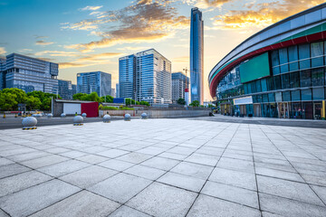 Fototapeta premium Empty large floor square with modern city buildings skyline including skyscrapers under dramatic sunset sky in Asia.