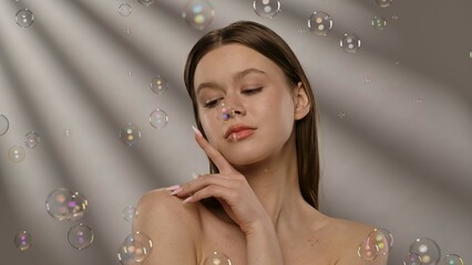 Beautiful Woman Surrounded by Floating Soap Bubbles in Soft Light