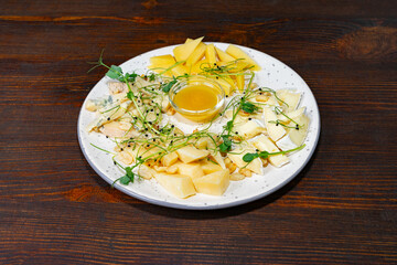 Cheese and fruit platter with honey served on wooden table