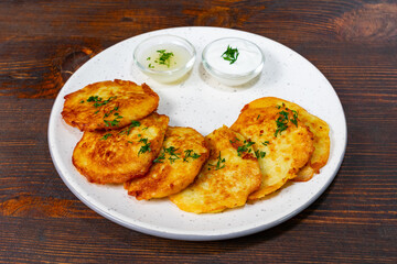 Delicious potato pancakes served with creamy dips on wooden table
