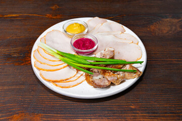 Delicious platter of sliced meats and sauces on wooden table