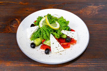 Fresh salad with greens, tomatoes, cucumber, and cheese on a plate
