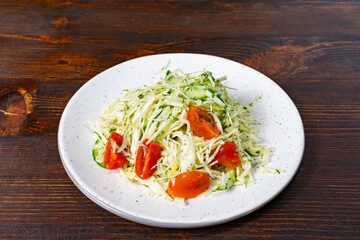 Fresh vegetable salad with cabbage and tomatoes on wooden table