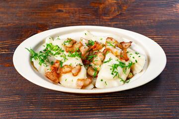 Traditional dumplings with crispy bacon on a wooden table