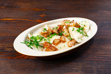 Delicious dumplings topped with crispy pork and herbs on wooden table